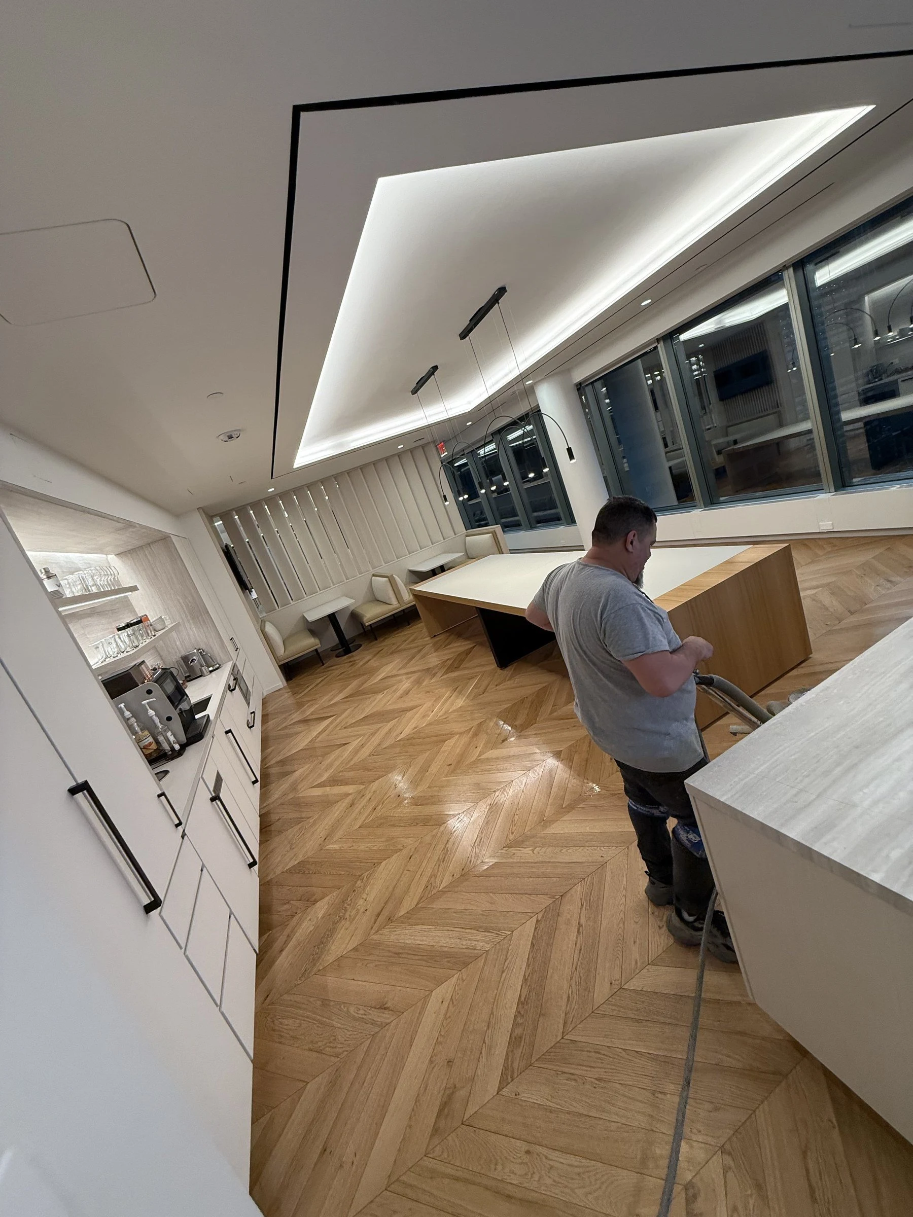 A Luxor technician operating a floor machine on a herringbone wood floor