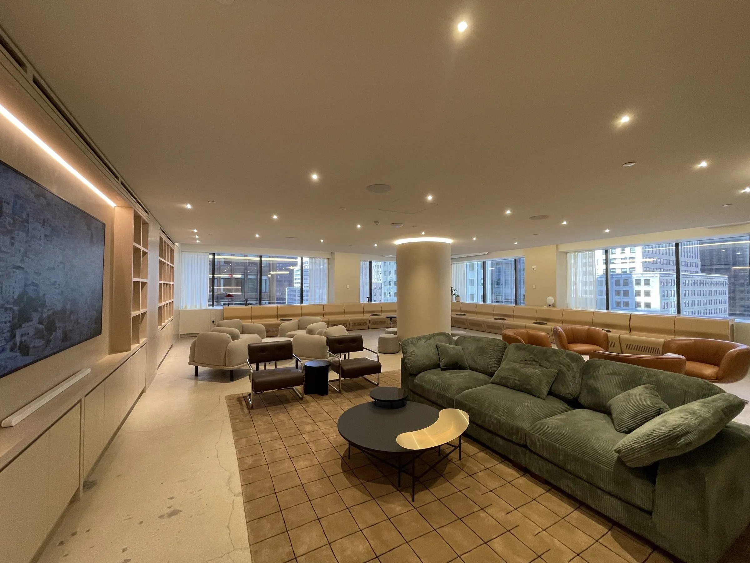A finished Manhattan amenity lounge, with polished floors, walnut millwork and green velvet seating